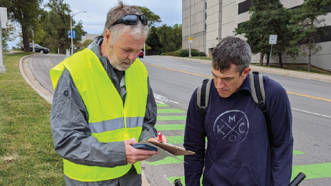 BikeWalk volunteer in a high visibility vest collects feedback from cyclist on the Gillham bike lane